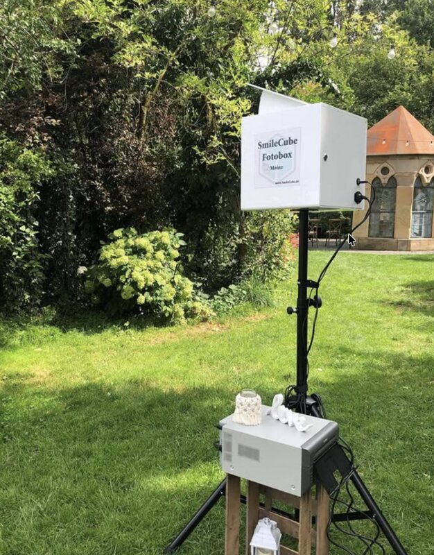 SmileCube Fotobox im Garten mit Kirche im Hintergrund