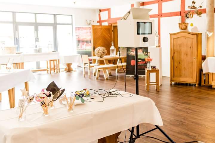 SmileCube Fotobox mit Requisiten auf einer Hochzeitsfeier im Festsaal