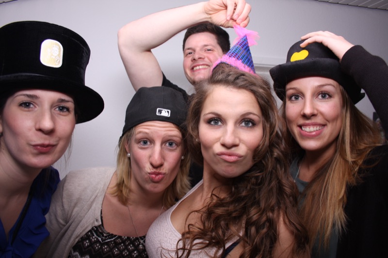 Fröhliche Gruppe mit Hüten und Caps an der SmileCube Fotobox